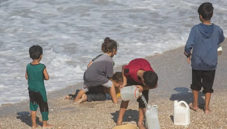 (FILE) Palestinian children fill water containers on Khan Yunis beach in the southern Gaza Strip, 29 November 2023. Photo: EFE.